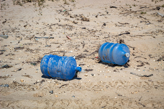 two blue plastic carboys on seashore