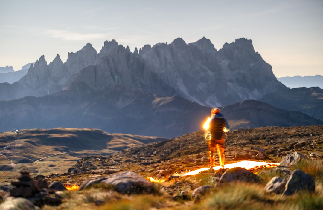 Hiker illuminated by sunset against mountain range.