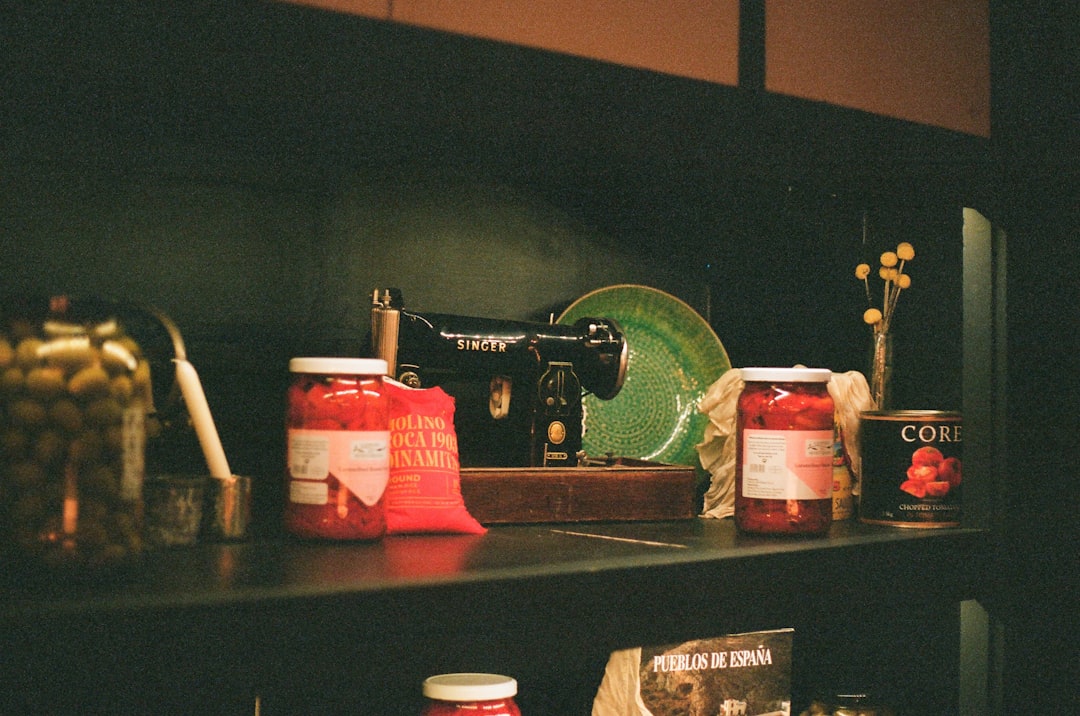 Jars of food and a sewing machine on a shelf.